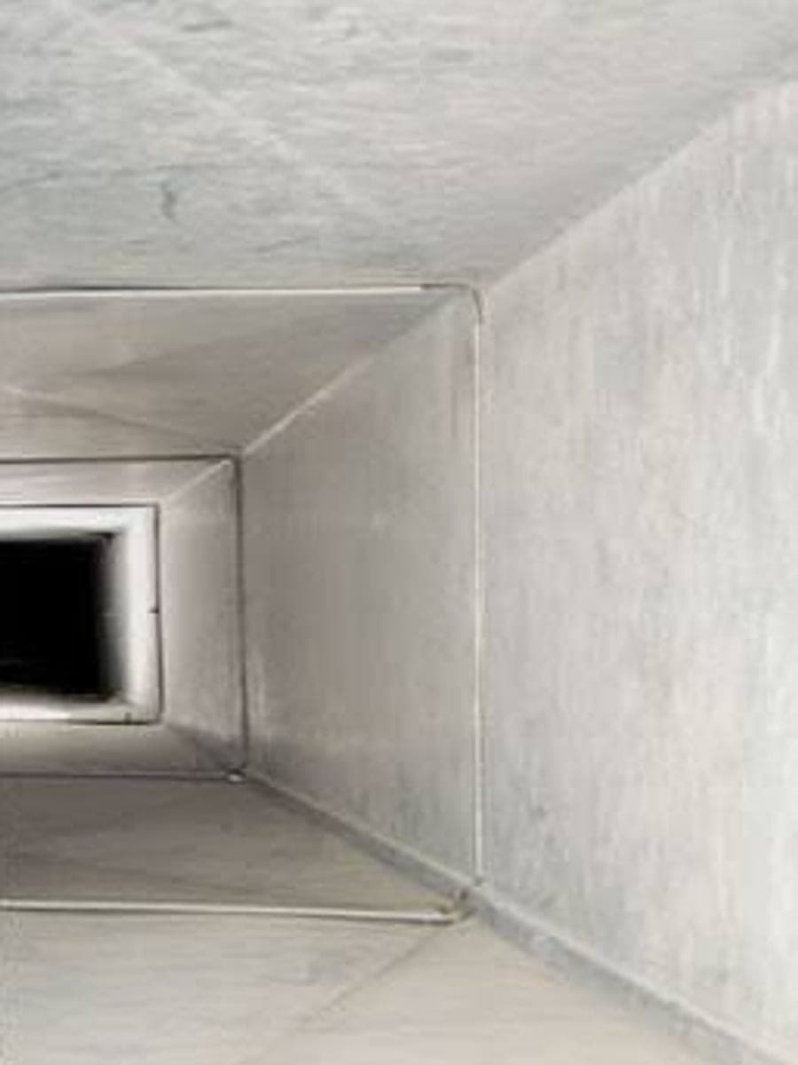 Inside a rectangular supply duct, lined with dust and debris before cleaning and bare metal afterwards