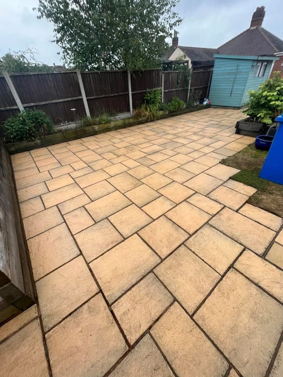 A paved patio grey with algae and grime before washing, restored to clean stone afterwards